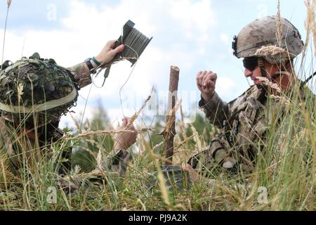 U.S. Army Staff Sgt. Robert Moore (rechts), auf das erste Geschwader zugewiesen sind, 2.Kavallerie Regiments, hilft bei der britischen Armee LT. Tom Chapman (links), 1. die Queen's Dragoon Guards zugewiesen, bis M18 A1 Claymore Mine während eines multinationalen claymore Ausbildung Übung mit Battle Group Polen Bemowo Piskie, Polen am 10. Juli 2018 eingestellt. Battle Group Polen ist ein einzigartiges, multinationale Koalition von USA, Großbritannien, Kroatischen und rumänischen Soldaten, die mit der polnischen 15 mechanisierte Brigade als Abschreckung Kraft zur Unterstützung des NATO-Enhanced vorwärts Präsenz dienen. Stockfoto