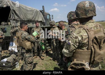 Us Marine Corps Staff Sgt. David Nunez die Batterie gunnery Sergeant der Echo-Akku, 2. Bataillon, 10 Marine Regiment (2/10), 2nd Marine Division, zeigt Nationen besuchen die Grundierung für den M777 Haubitze in Salisbury, England, Juli 5, 2018. Marines mit der Unit durchgeführt live-fire Übungen mithilfe der M777 Haubitze während der Übung grüne Kanone 18. Grüne Kanone ist eine multinationale Übung mit US-Marines die Möglichkeit, Taktiken und Techniken sowie zu Exchange Projekt Letalität und Combat Power auf der ganzen Welt neben Partner Nationen. Stockfoto