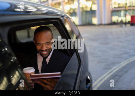 Geschäftsmann Kaffee trinken und Verwendung digitaler Tablet in crowdsourced Taxi Stockfoto
