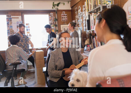 Kreative Designer spielen Ukulele im Büro Stockfoto