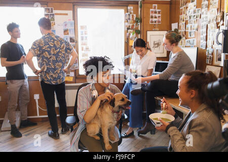 Creative Business Leute mit Hund arbeiten und essen im Büro Stockfoto