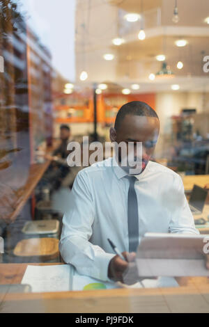 Geschäftsmann mit digitalen Tablette, die in Fenster Cafe Stockfoto