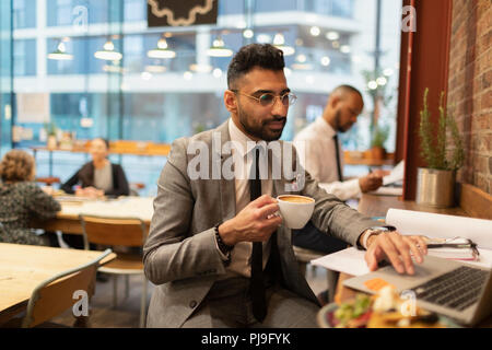 Konzentrierte Geschäftsmann Kaffee trinken und Arbeiten am Laptop im Cafe Stockfoto