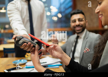 Geschäftsfrau bezahlen mit smart phone kontaktloses Bezahlen im Café Stockfoto