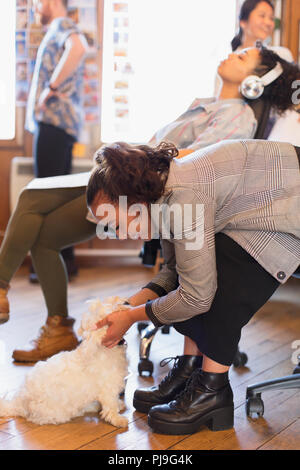 Kreative Geschäftsfrau petting niedlichen Hund im Büro Stockfoto