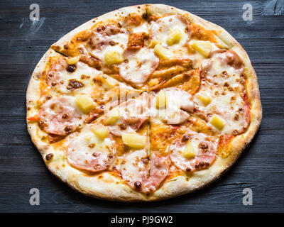 Italienische Pizza mit Schinken und Ananas auf Dunkelbraun Holzbrett Stockfoto