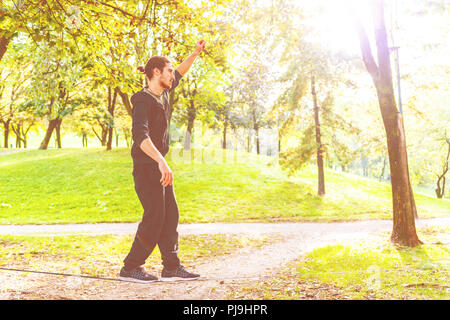Junger Mann outdoor Park slacklining - Balance, Sport, Gratwanderung Konzept Stockfoto