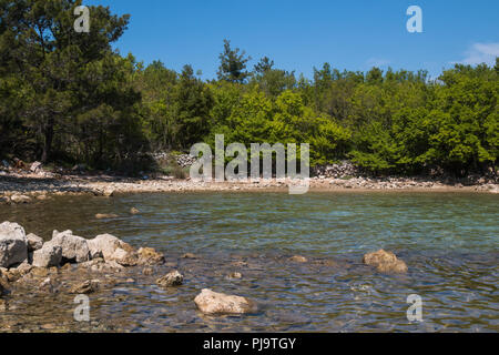 Große Steine an der Küste und in das saubere und klare Wasser der Adria. Grüne Wälder säumen die Küste. Insel Krk, Kroatien. Stockfoto