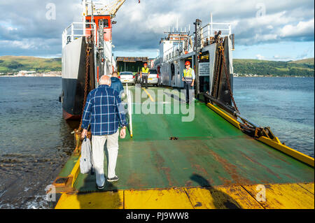 Die Fluggäste die Ro-Ro-Fähre Loch Riddon von der Insel Cumbrae, mit der Küstenstadt Desination von Largs im Hintergrund. Stockfoto