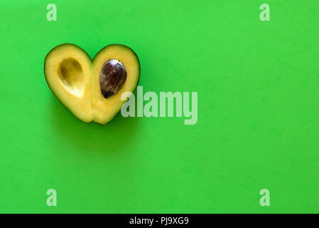 Heart-shaped Scheiben Avocado auf grünem Hintergrund Stockfoto