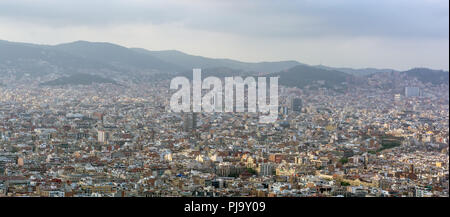 Blick auf die Stadt Barcelona von der Spitze des Montjuic Hügel in bewölkten Tag mit Ausbrüchen von Sonnenlicht. Die Skyline von Barcelona unter grauen Wolken. Stockfoto