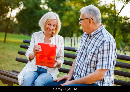 Ältere Frau freut sich über Geschenk von ihrem Mann. Stockfoto