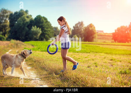 Junges Mädchen mit Labrador Retriever Hund Wandern auf dem Feld. Hund suchen auf das Mädchen Stockfoto