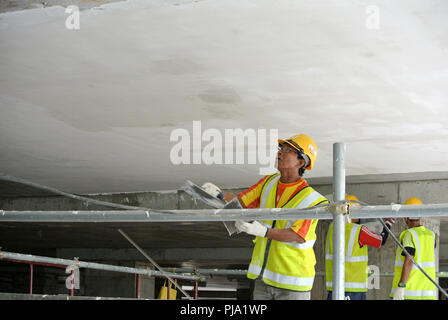 Baustelle Mitarbeiter Decke laibung Mantel Arbeit auf der Baustelle überfliegen. Basis- und Decklack Schicht auf die glatte Oberfläche zu erhalten. Stockfoto