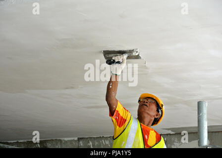 Baustelle Mitarbeiter Decke laibung Mantel Arbeit auf der Baustelle überfliegen. Basis- und Decklack Schicht auf die glatte Oberfläche zu erhalten. Stockfoto