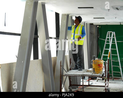 Baustelle Mitarbeiter Decke laibung Mantel Arbeit auf der Baustelle überfliegen. Basis- und Decklack Schicht auf die glatte Oberfläche zu erhalten. Stockfoto