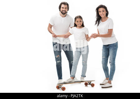 Lächelnd Eltern helfen Tochter Schlittschuhlaufen auf Skateboard isoliert auf weißem Stockfoto