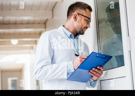 Seitenansicht des Tierarztes mit Zwischenablage überprüfen Zimmer im Tierärztlichen Klinik Stockfoto