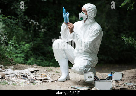 Männliche Wissenschaftler in der Schutzmaske und Klage auf Latex Handschuh im Wald Stockfoto