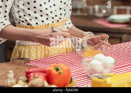 7/8 Schuß von hausfrau rühren, Eier für Omelette in Küche Stockfoto