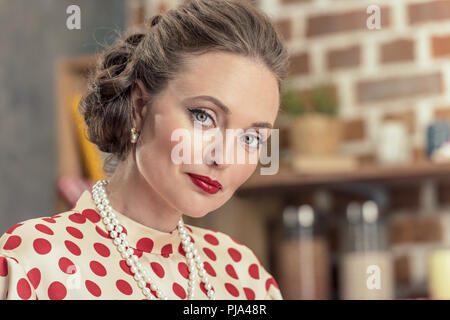 Nahaufnahme Porträt der Schönen erwachsenen Frau in vintage Polka Dot Shirt und Perlenkette an Kamera suchen Stockfoto