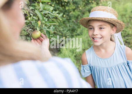 Mom und lächelnd entzückende Tochter Äpfel pflücken zusammen Stockfoto