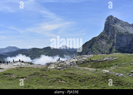 Pena Remona von El-Kabel an der Oberseite der Seilbahn von Fuente De. Menschen sind, genießen Sie den Sommer Sonnenschein vor eine dünne Linie von Nebel. Stockfoto