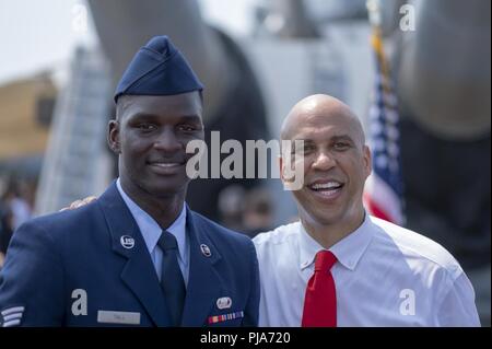 Us Air Force Senior Airman Alpha Oumar Ahamadou Hoch, Links, eine Karriere Entwicklung Techniker mit Unterstützung der 514th Squadron, 514Th Air Mobility Wing, posiert für ein Foto mit Sen Cory Booker von New Jersey an Bord das Schlachtschiff New Jersey Museum und Gedenkstätte, in Camden, New Jersey, 4. Juli 2018. Booker ausgeliefert, die Ansprache an die US-Bürger und Immigration Services Zeremonie, an der Hohen eingebürgert wurde. Ursprünglich aus Mali, Groß ist das zweite Mitglied seiner Familie in den amerikanischen Streitkräften zu dienen und die ersten als Reserve Bürger Flieger zu dienen. Die 514Th ist ein Air Force Stockfoto