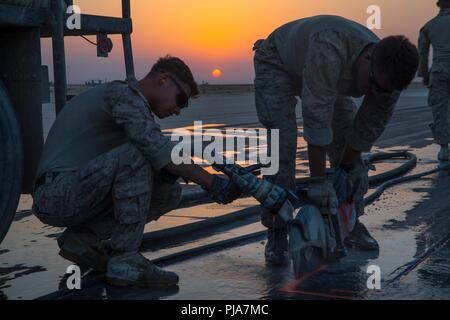 Unbekannten ORT, NAHER OSTEN - US Marine Corps Cpl. Joshua Garza (links), eine kleine Arme reparatur techniker, und LCpl Connor Reid (rechts), eine Bekämpfung der Ingenieur mit Marine Wing Support Squadron 371, Special Purpose Marine Air-Ground Task Force angebracht, Krise Response-Central Befehl schnitt durch Pflaster eine beschädigte Flugplatz am 3. Juli 2018 zu reparieren. Der Flugplatz Schäden reparieren Team sorgt für Start- und Landebahnen sicher sind Flugbetrieb in der gesamten Region durchzuführen. Stockfoto