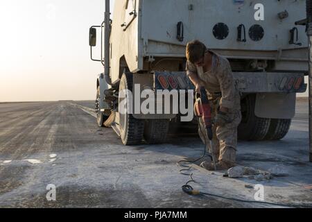 Unbekannten ORT, NAHER OSTEN - US Marine Corps Cpl. Evelyn Jones, einen Admin und Operations Specialist mit Marine Wing Support Squadron 371, Special Purpose Marine Air-Ground Task Force angebracht, Krise Response-Central Befehl löscht einen Abschnitt der Fahrbahn während der Reparatur eines beschädigten Flugplatz Juli 3, 2018. Der Flugplatz Schäden reparieren Team sorgt für Start- und Landebahnen sicher sind Flugbetrieb in der gesamten Region durchzuführen. Stockfoto