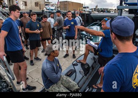 PEARL HARBOR (6. Juli 2018) Marine Taucher, zugeordnet zu den Mobilen Tauchen retten (MDSU) 1 ein Briefing vor dem Tauchgang Verhaltensweisen vor Tauchen auf der USS Arizona Memorial während der Rand der Pazifischen (Übung RIMPAC) 2018, 7. Juli zu. 25 Nationen, 46 Schiffe, 5 U-Boote, über 200 Flugzeuge, und 25.000 Mitarbeiter beteiligen sich an Rimpac vom 27. Juni bis 2. August in und um die hawaiischen Inseln und Südkalifornien. Die weltweit größte internationale maritime Übung RIMPAC bietet eine einzigartige Ausbildung während der Förderung und Erhaltung der kooperative Beziehungen unter den Teilnehmern cr Stockfoto