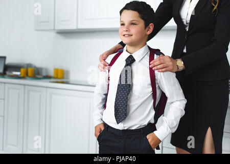 Teilansicht von Mutter und Sohn in der Schule Uniform mit Rucksack in der Küche zu Hause, zurück in die Schule Konzept Stockfoto