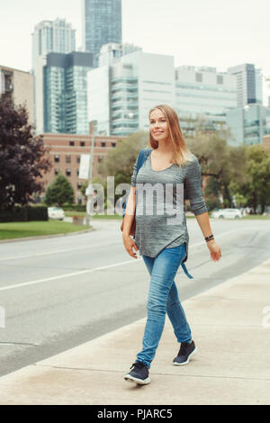 Glückliche gesunde Schwangerschaft. Portrait der kaukasischen schwangere junge blonde kaukasische Frau wandern in belebten Stadt außerhalb. Schöne schlanke sportliche erwarten Stockfoto