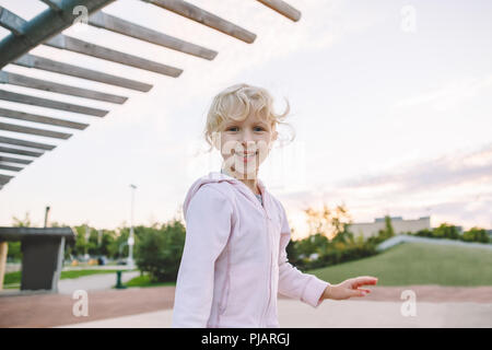 Glückliche Kindheit. Portrait von cute adorable kleine blonde Kaukasische Mädchen, lustig dumme Gesichter. Kid spielen Spaß im Park außerhalb an Sonnen Stockfoto