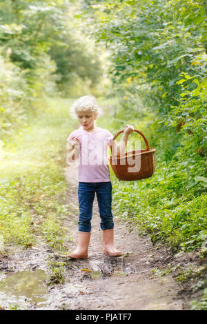 Cute adorable white Kaukasischen blond Vorschule Mädchen pflücken frische Speisepilze im Weidenkorb. Herbst Herbst Aktivität hobby Konzept. Stockfoto