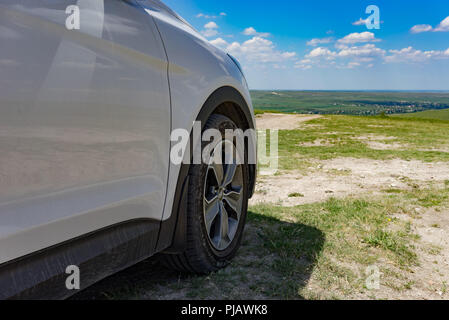Teil der weißen SUV mit dem Rad auf dem Hintergrund der natürlichen Landschaft in der Sonne. Stockfoto