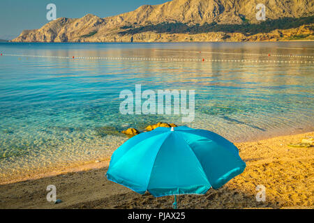 Ein einsamer Sonnenschirm am Strand bei Tagesanbruch am Wasser der Adria in Baska auf der Insel Krk Stockfoto