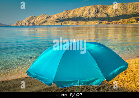 Ein einsamer Sonnenschirm am Strand bei Tagesanbruch am Wasser der Adria in Baska auf der Insel Krk Stockfoto