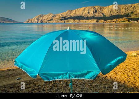 Ein einsamer Sonnenschirm am Strand bei Tagesanbruch am Wasser der Adria in Baska auf der Insel Krk Stockfoto