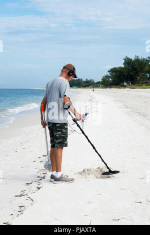 Ein Mann mit einem Metalldetektor für Schätze auf der Anna Maria Island Beach, Florida, USA zu suchen Stockfoto