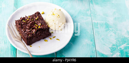 Chocolate Brownie, Kuchen auf einem weißen Teller auf einem türkis Holz- Hintergrund. Kopieren Sie Platz. Stockfoto