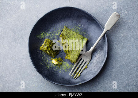 Matcha grüner Tee Kuchen, Bars, Brownie mit weißer Schokolade auf einem Teller. Grauer Hintergrund. Ansicht von oben. Stockfoto