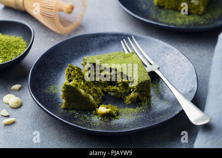 Matcha grüner Tee Kuchen, Bars, Brownie mit weißer Schokolade auf einem Teller. Grauer Hintergrund. Stockfoto