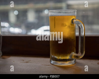 Große frosty Bierkrug mit Lager sitzen auf Zähler nach oben gefüllt Stockfoto