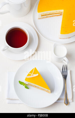 Passion fruit cake, Mousse Dessert auf eine weiße Platte mit Tasse Tee. Ansicht von oben. Stockfoto