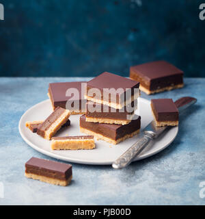 Schokolade Karamell Schichten, Bars, Millionäre shortbread auf einem Teller. Blauen Hintergrund. Kopieren Sie Platz. Stockfoto