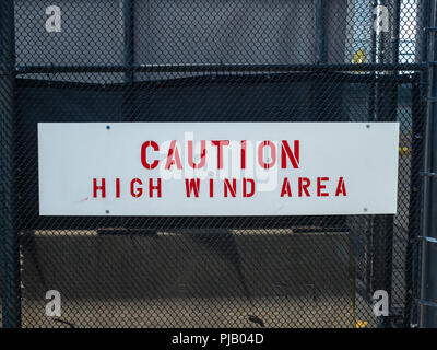 Vorsicht High Wind Area anmelden die Weitergabe der schwarze Zaun Stockfoto