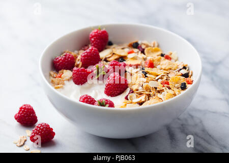 Gesundes Frühstück. Frisches Müsli, Müsli mit Joghurt und Beeren auf Marmor Hintergrund. Stockfoto