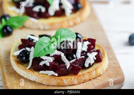 Bruschetta mit gebackenen Rüben, Blaubeeren, FETA-Käse, Basilikum und Balsamico. Gourmet Snack. Gesunde Ernährung. Selektiver Fokus Stockfoto