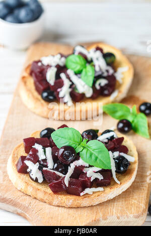 Bruschetta mit gebackenen Rüben, Blaubeeren, FETA-Käse, Basilikum und Balsamico. Gourmet Snack. Gesunde Ernährung. Selektiver Fokus Stockfoto